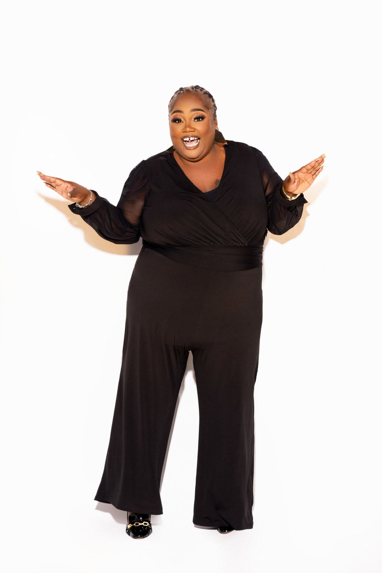 Oneshia in a black outfit, arms open